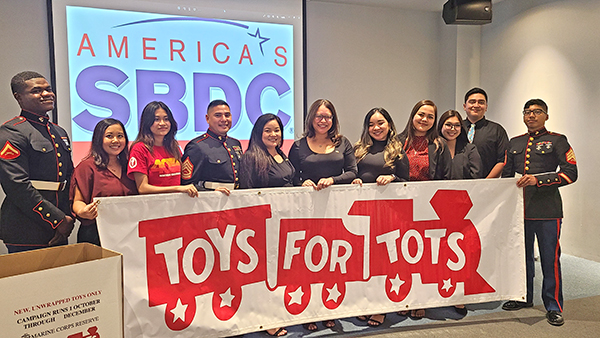 PROA director and OSAL acting manager Kaelani Demapan, ASNMC president Anushi Joshi, SBDC’s Mercilynn Palec and Nadine Deleon Guerrero are flanked by U.S. Marines behind the Toys for Tots banner after the Saipan Chamber of Commerce monthly meeting last Wednesday at the Kensington Hotel Saipan. (Chrystal Marino)