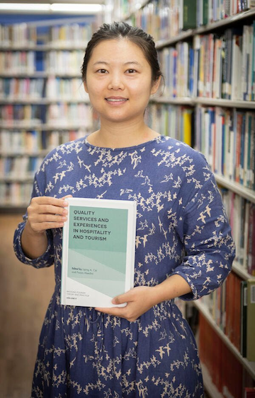 Dr. Yunzi Zhang with a book she contributed to. The chapter she wrote, “Quality Experiences of China's Family Tourists in the United States,” was recognized as an Outstanding Author Contribution in the 2019 Emerald Literati Awards.