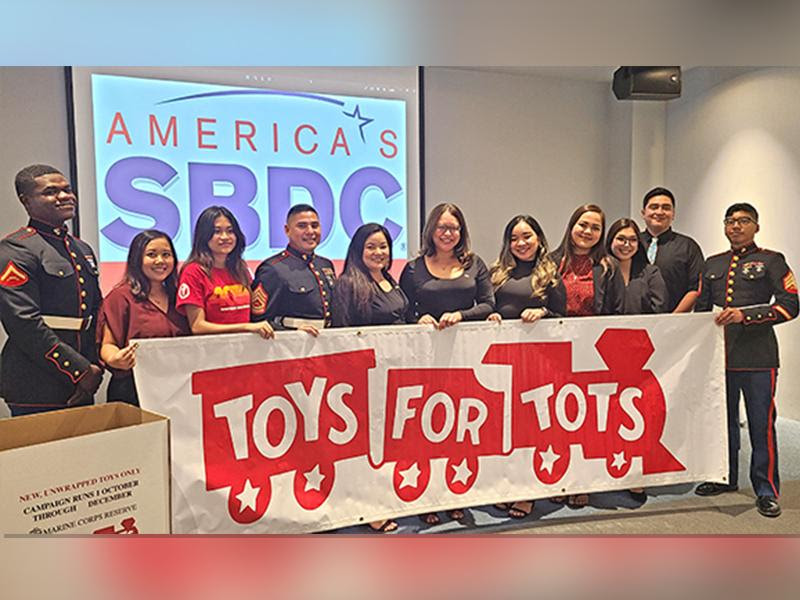 PROA director and OSAL acting manager Kaelani Demapan, ASNMC president Anushi Joshi, SBDC’s Mercilynn Palec and Nadine Deleon Guerrero are flanked by U.S. Marines behind the Toys for Tots banner after the Saipan Chamber of Commerce monthly meeting last Wednesday at the Kensington Hotel Saipan. (Chrystal Marino)